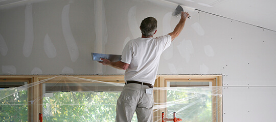 A contractor repairing a wall.