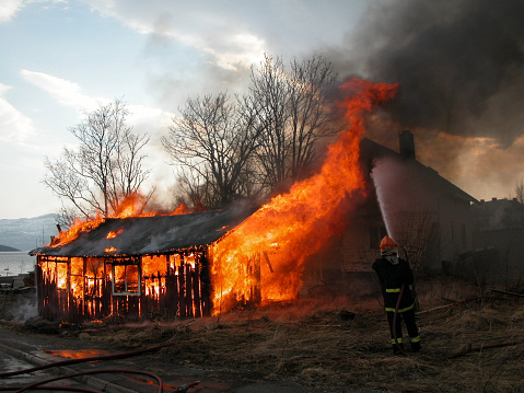 burning building with firefighter spraying water.
