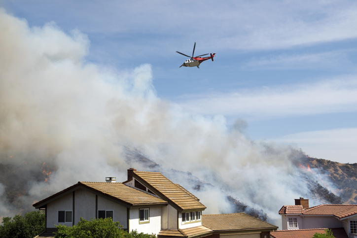 helicopter over wildfire and homes.
