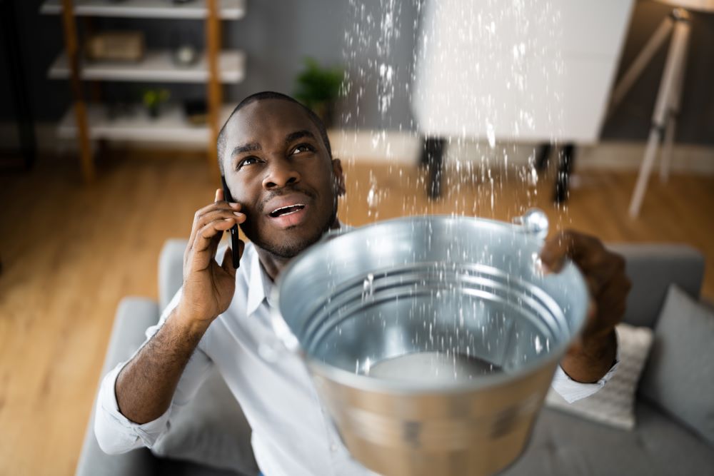 Man catching leak in bucket.