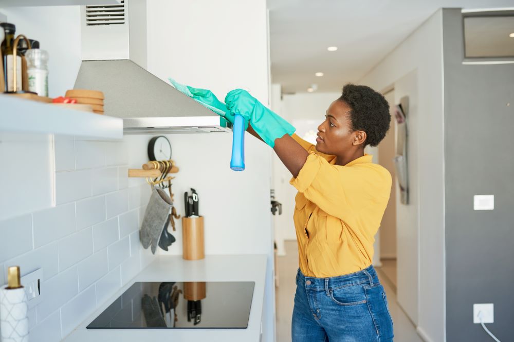 Woman cleaning oven hood.